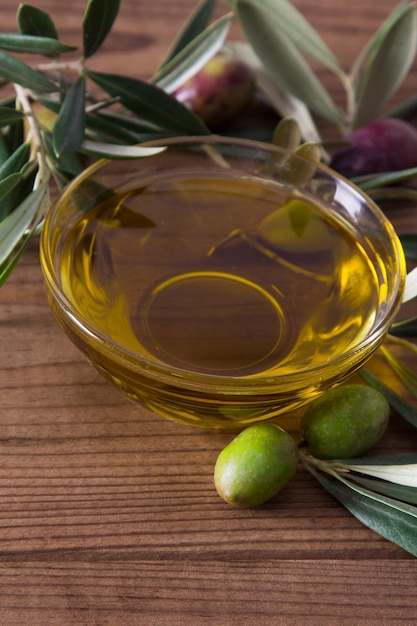 Photo glass vessel with extra virgin olive oil and olives with branch