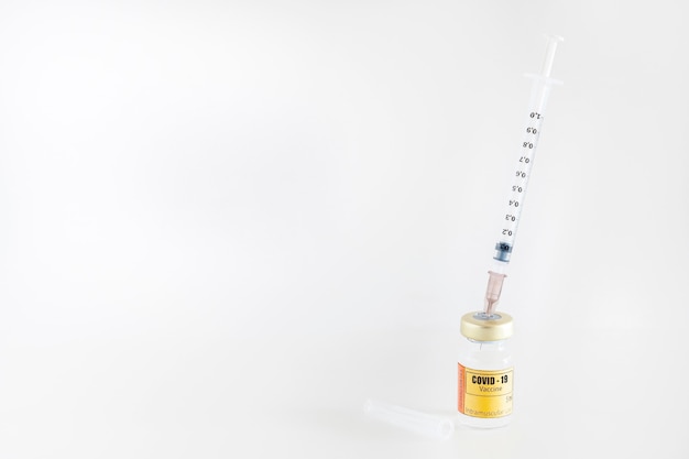 Glass vial for intramuscular injection containing the vaccine for covid19 with syringe and needle on white background