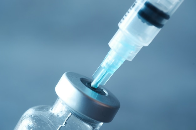 Glass vial and syringe on black background .