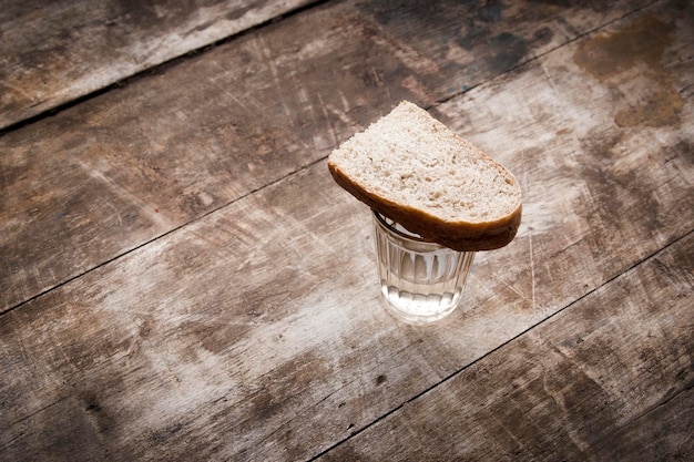 ウォッカのグラスと木製のテーブルの上のパン
