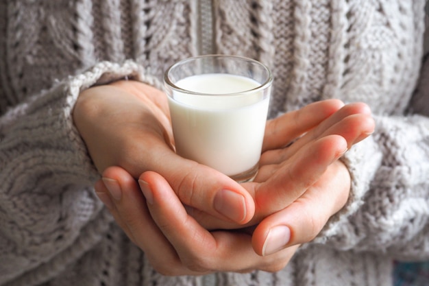 A glass of warm milk in hand in the winter.