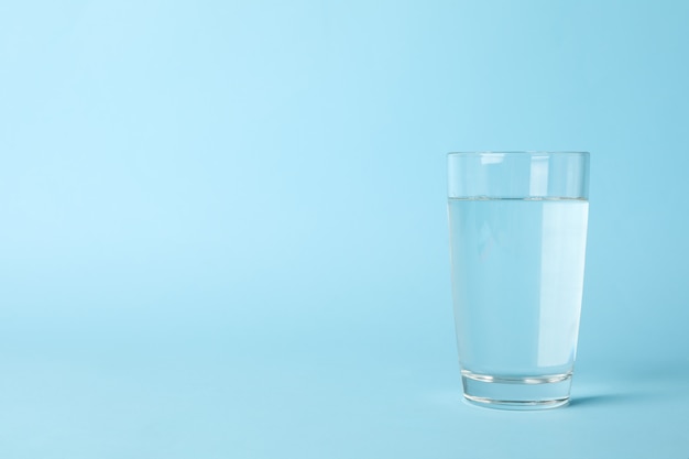 Glass of water on blue, space for text