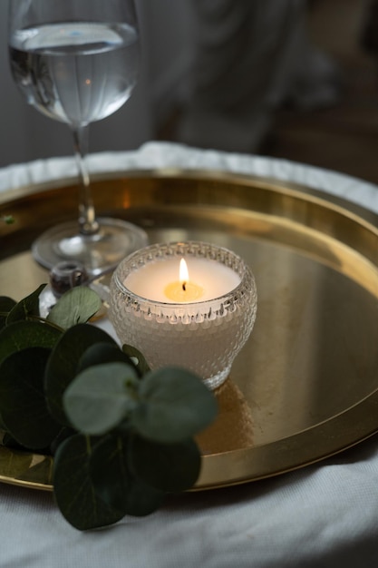 A glass of water and a candle on a gold tray