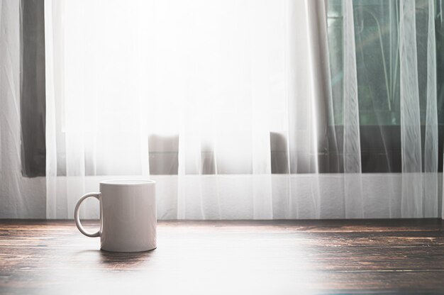 A glass of water and a coffee mug are at the desk.