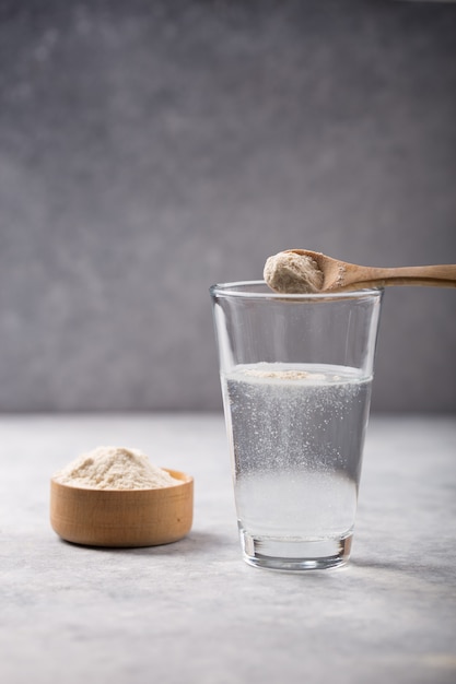 Foto bicchiere d'acqua, polvere di collagene sulla tavola bianca. concetto di stile di vita sano. copia spazio