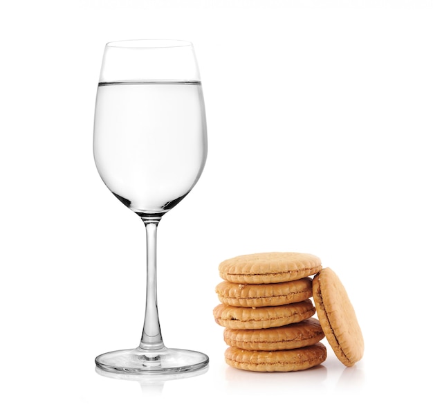 Glass of water and cookies on white background