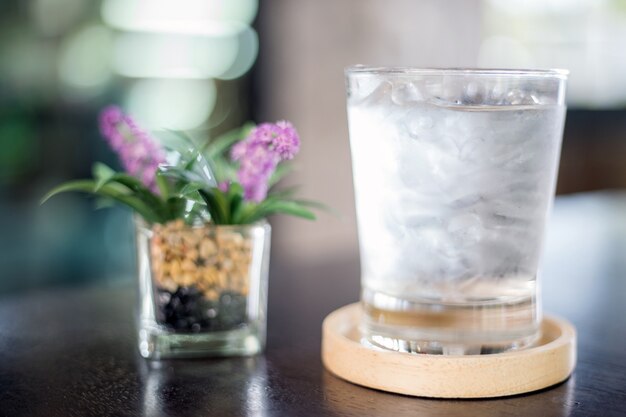 木のテーブルに水と偽の花のガラス