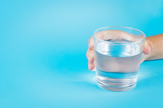 Glass of water in hand on blue