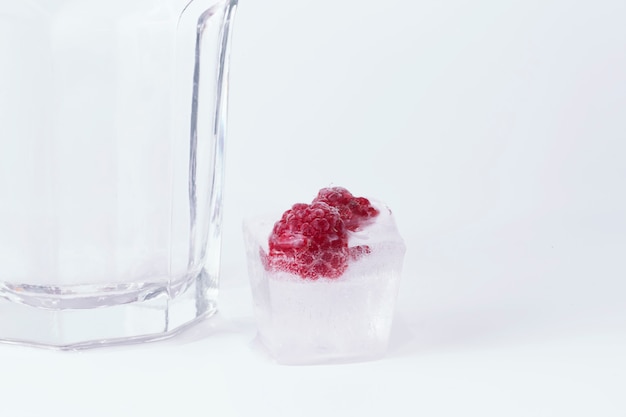 Glass of water ice raspberries on a white background