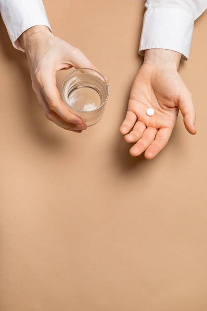 Glass of water and medicine in hand