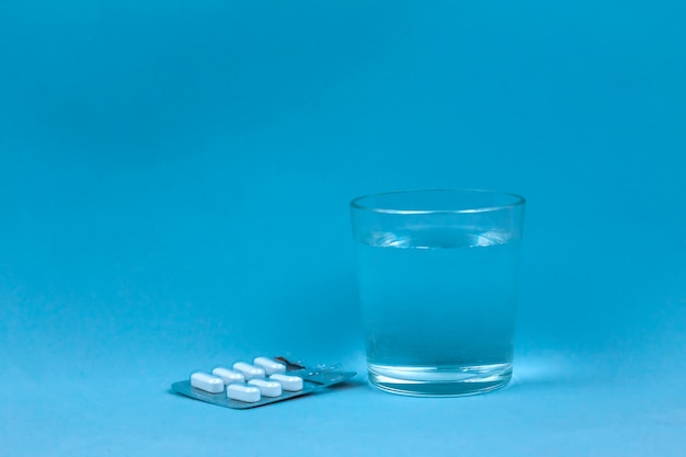 Glass Of Water And Pills On Blue Background