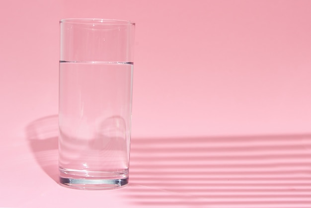 Glass of water on pink background