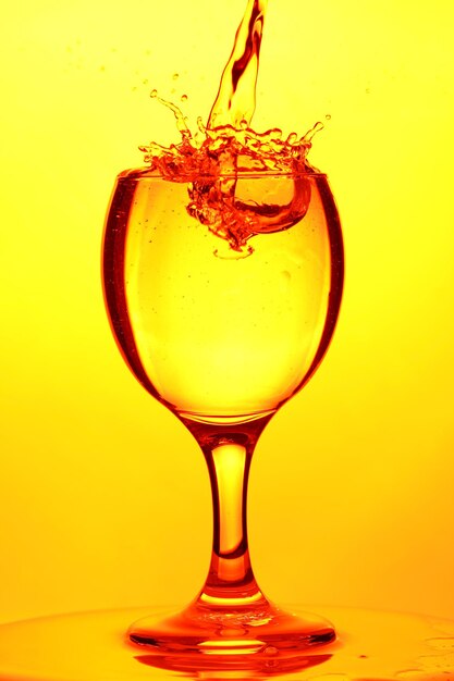 Glass of water. Splash of water in a glass on yellow