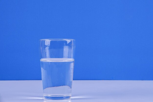 Glass of water on table against blue background