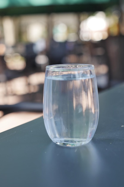 Glass of water on table on blur cafe background