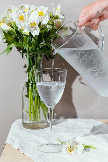 Foto bicchiere d'acqua e vaso con fiori