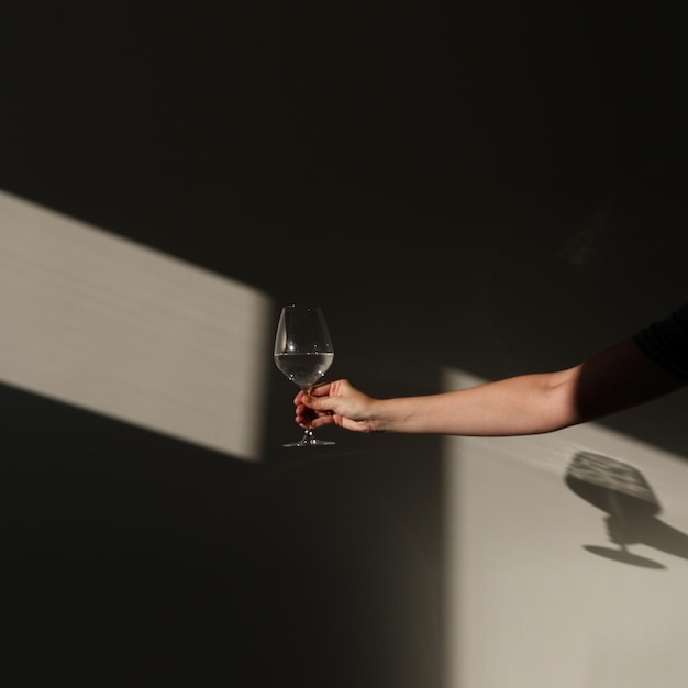 a glass of water on a white background with a shadow chiaroscuro from the window closeup copy space