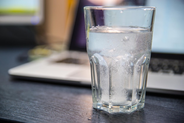 Glass of water with aspirin. laptop on background. overloaded with office work