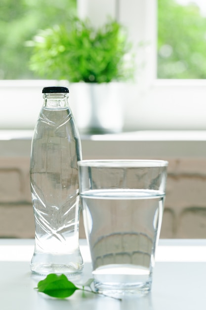 Bicchiere d'acqua con una bottiglia sul tavolo