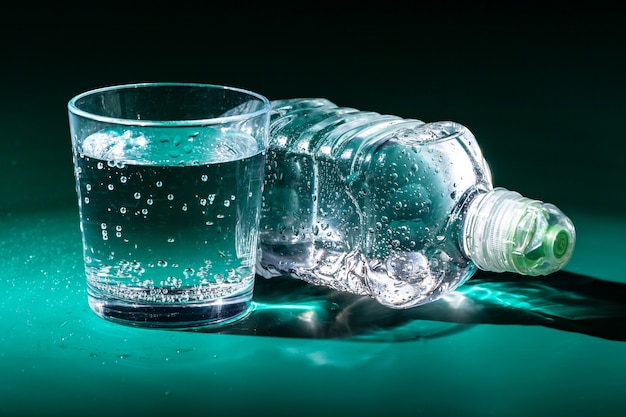 Glass of water with a bottle on table