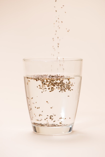 Glass of water with cup of healthy chia seeds and spoon. Text space.