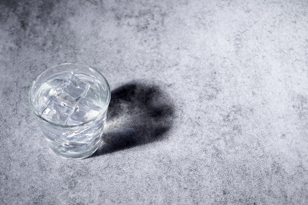 Glass of water with ice cubes projecting a reflexion