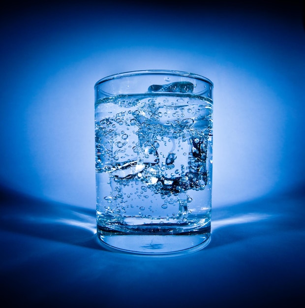 Glass of water with ice on a dark blue background