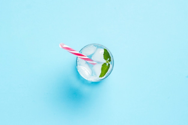 Glass of water with ice and mint on a blue background. Concept of hot summer, alcohol, cooling drink, thirst quenching, bar. Flat lay, top view