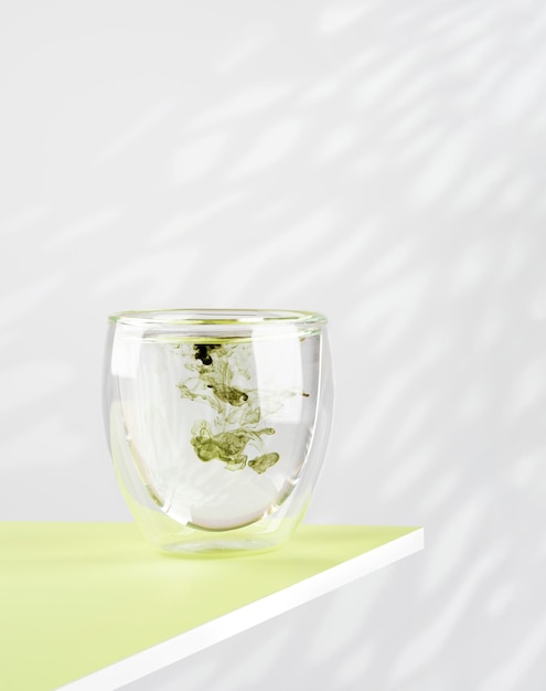 Glass of water with liquid chlorophyll on a green table Natural light white background vertical Copy space Concept of superfood healthy eating detox and diet