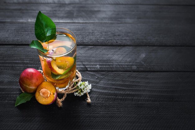 A glass of water with pieces of plums and apricont inside. Copy space. Healthy food, detox