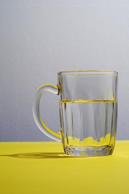 Foto un bicchiere d'acqua su uno sfondo giallo