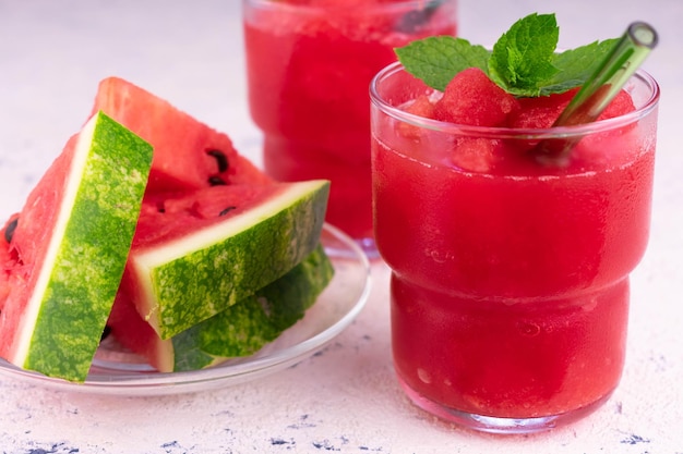 A glass of watermelon juice next to a glass of watermelon juice