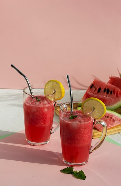 A glass of watermelon smoothie with ice, mint and lemon