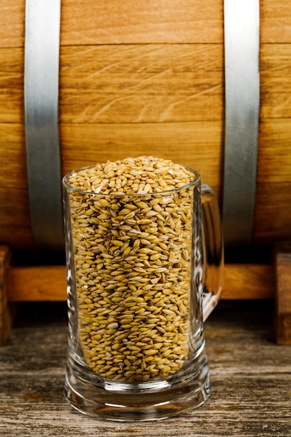 Foto un bicchiere di grano o malto accanto a una botte di legno