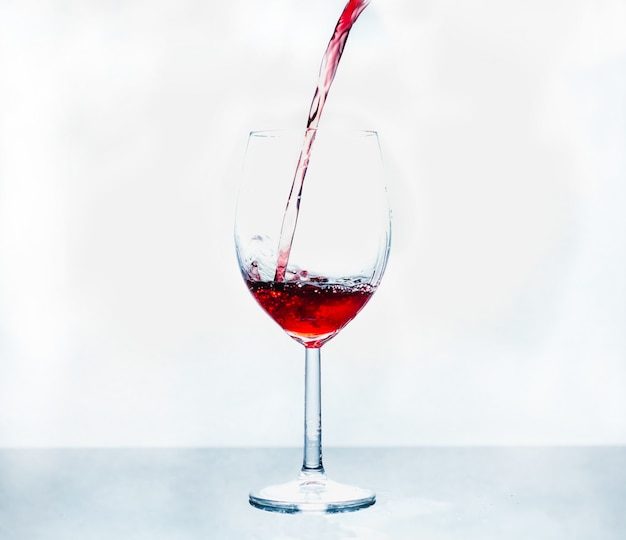 A glass in which is poured red wine on abstract background