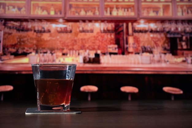 Glass of whiskey on the bar in front of the blur image pocket watch