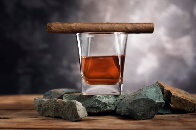 Photo glass of whiskey and cigar on stone