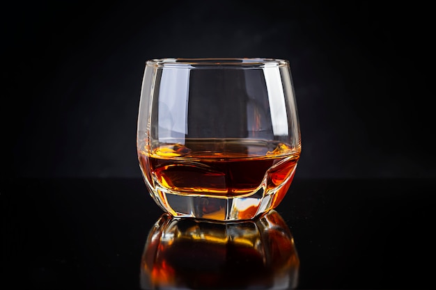 Glass of whiskey on dark background.