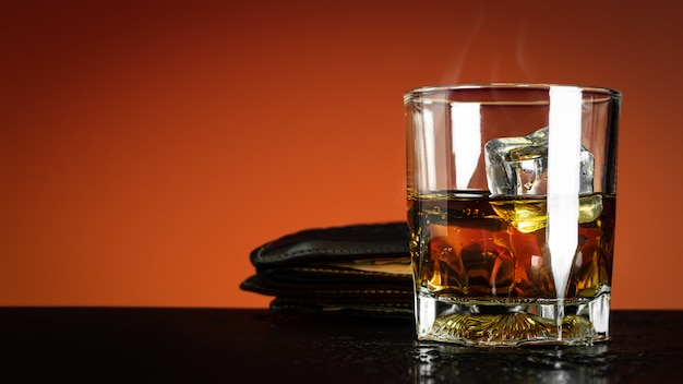 Bicchiere di whisky e cubetto di ghiaccio su rosso