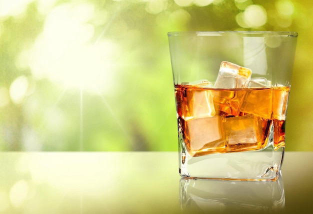 Glass of whiskey and ice isolated on light background