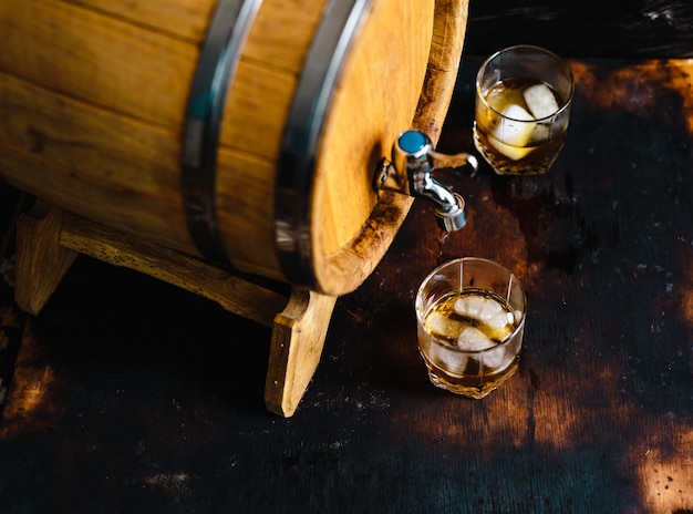 A glass of whiskey sitting on a wooden barrel