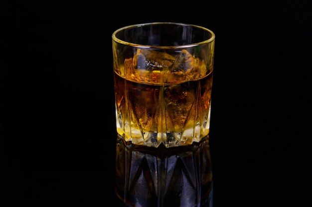 Glass of whiskey with ice on a black background