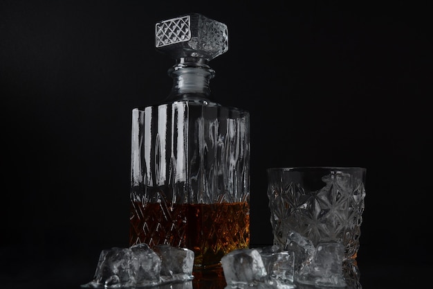 Foto bicchiere di whisky con cubetti di ghiaccio e un decanter quadrato