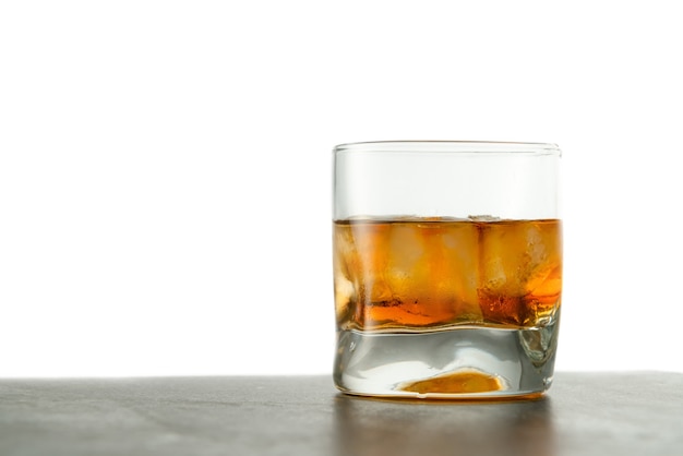 Glass of whiskey with ice cubes on the table.