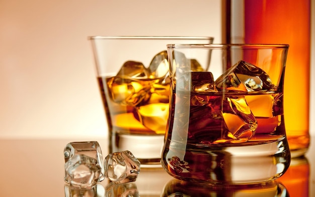 Foto un bicchiere di whisky con ghiaccio e cubetti di ghiaccio