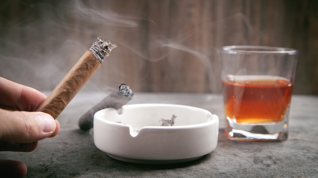 Photo glass of whisky, ashtray and cigars on the table.