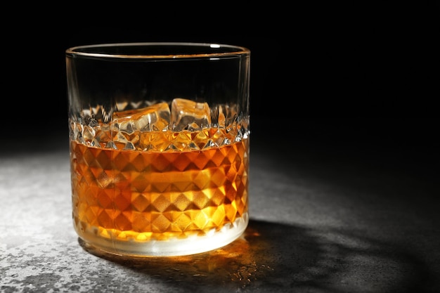 Glass of whisky on grey textured table closeup