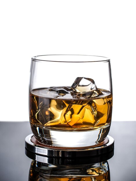 Glass of whisky on the rocks on white background