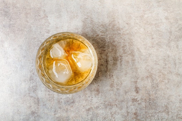 A glass of whisky with ice on a marble