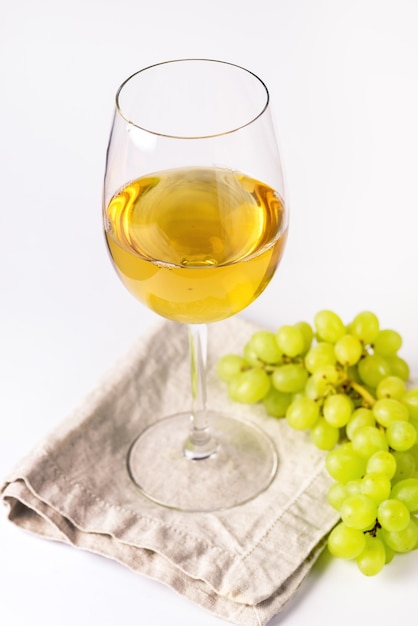 Glass of White Wine and Branch of Green Grapes on White Background